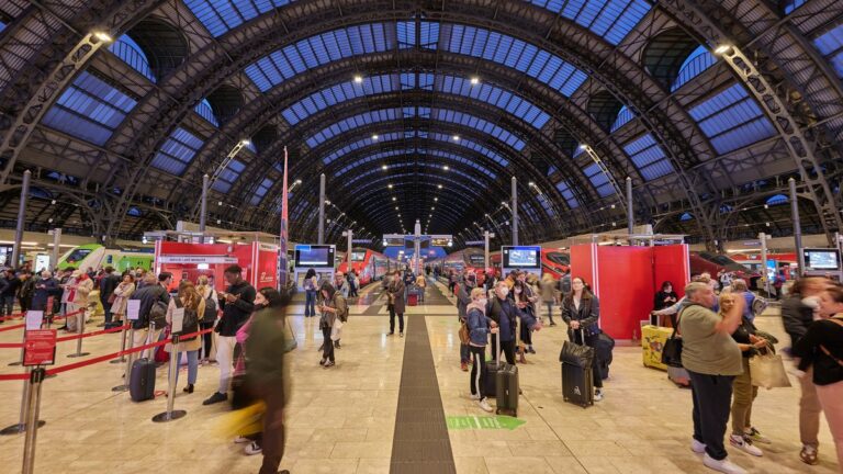 Viaggiatori con valigie e trolley sui binari della stazione di Milano Centrale